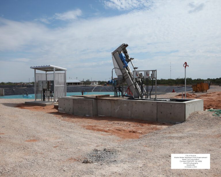 About a water reclamation facility under construction, featuring open excavation areas, machinery, and temporary structures under a clear sky.