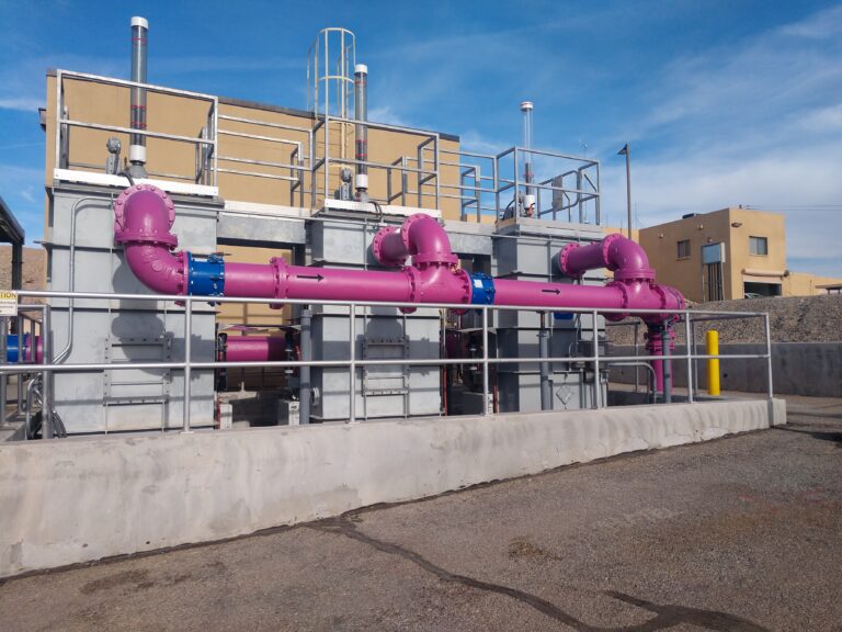 Industrial water treatment facility in Lake Havasu City with large pink pipes and steel structures under a clear blue sky.