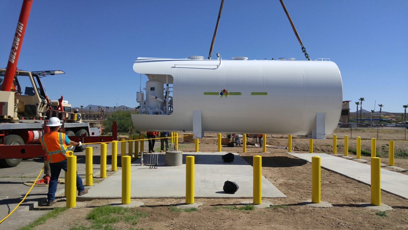 Large white fuel farm tank being installed at a construction site in San Carlos with a crane and workers in safety gear.