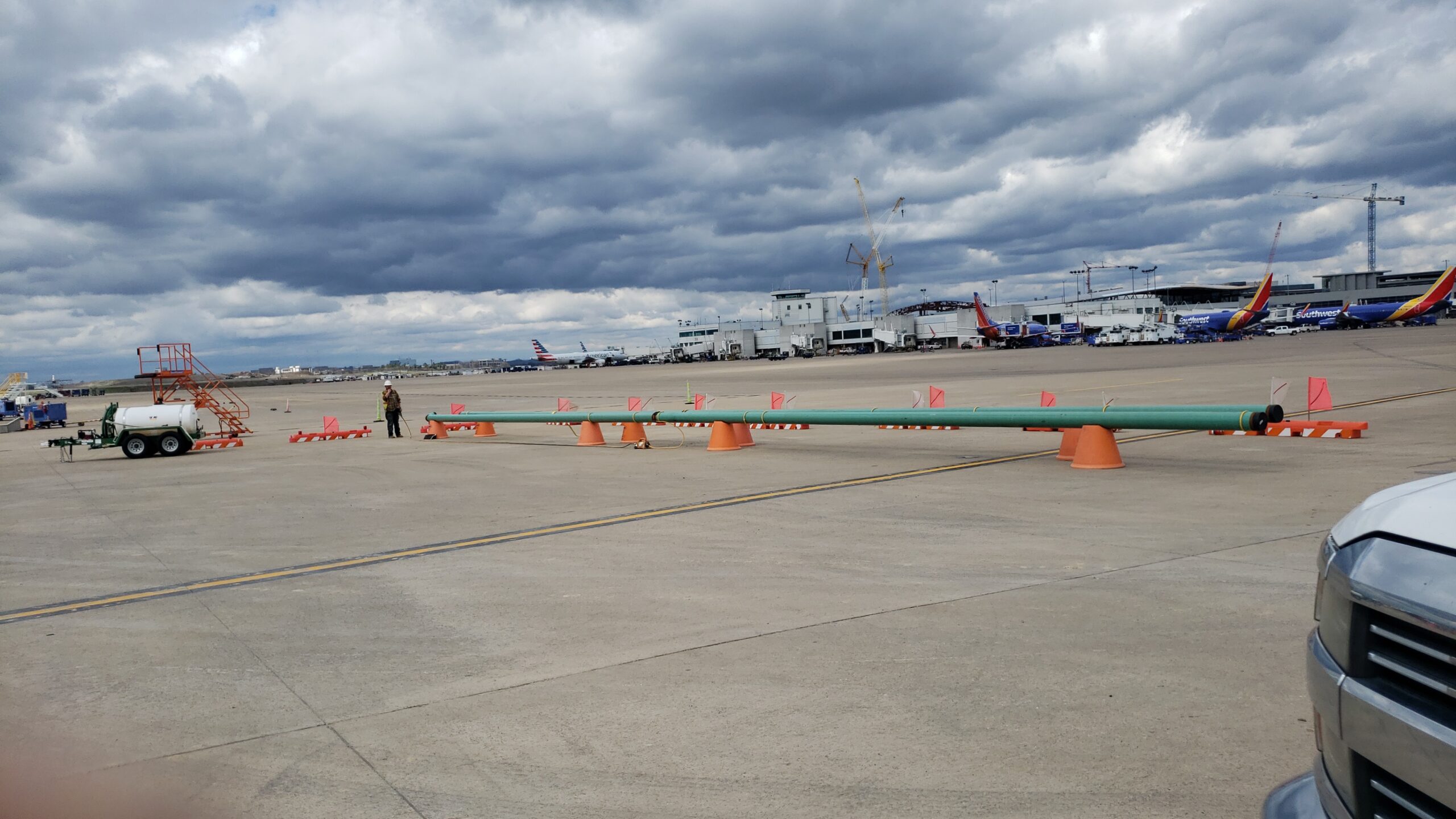 Airport tarmac at Nashville International Airport with safety cones, aircraft, and ground handling equipment under a cloudy sky.