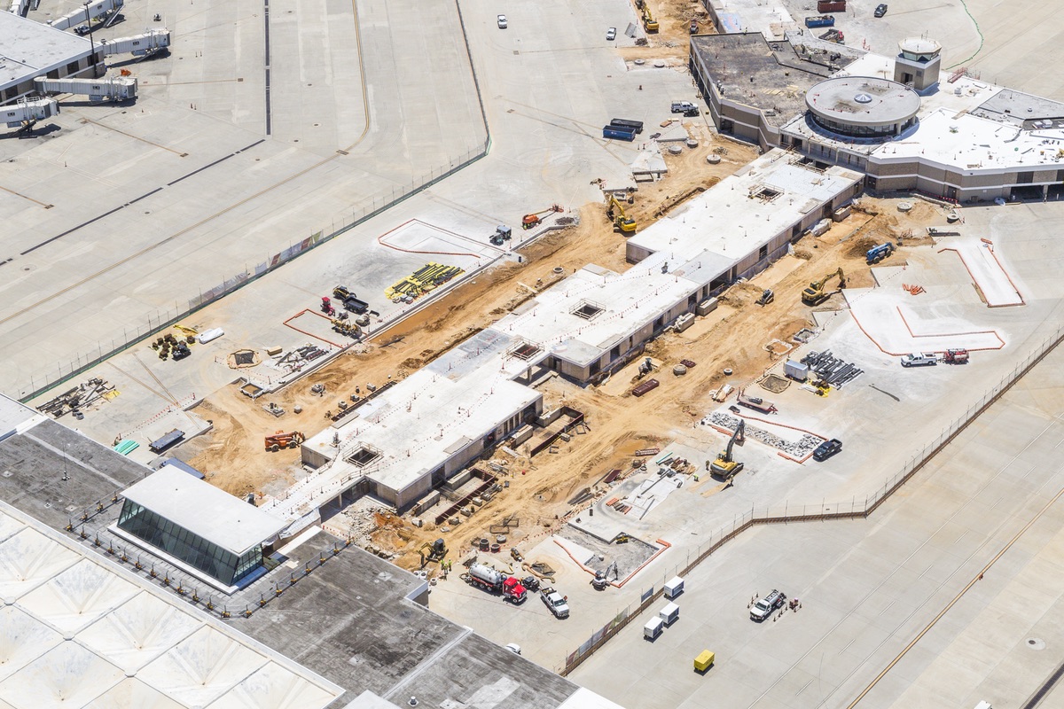 Aerial view of the ongoing Concourse Modernization at Memphis International Airport, featuring buildings under construction and heavy machinery scattered around.