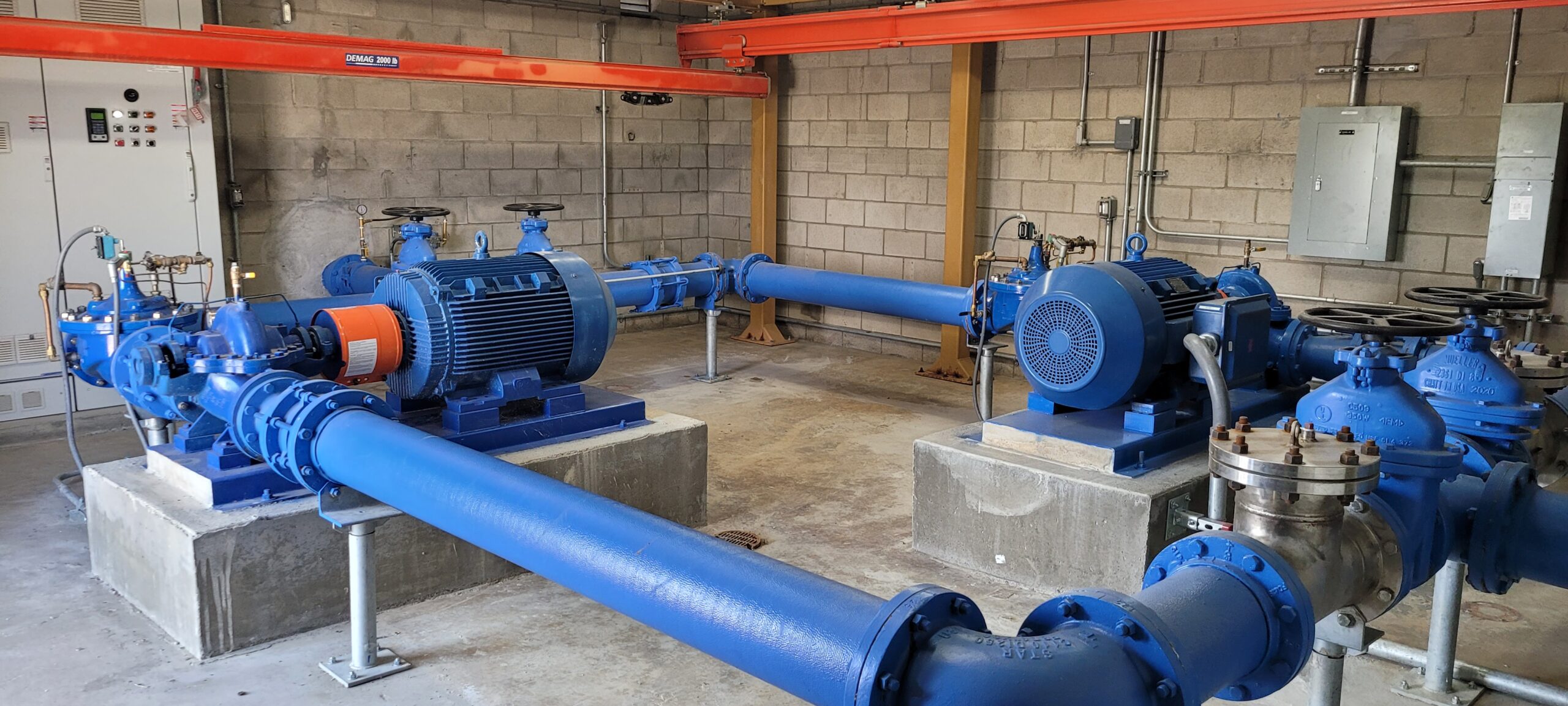Industrial water pumping station at Camp Pendleton with large blue pipes and electric motors mounted on concrete bases in a utility room.